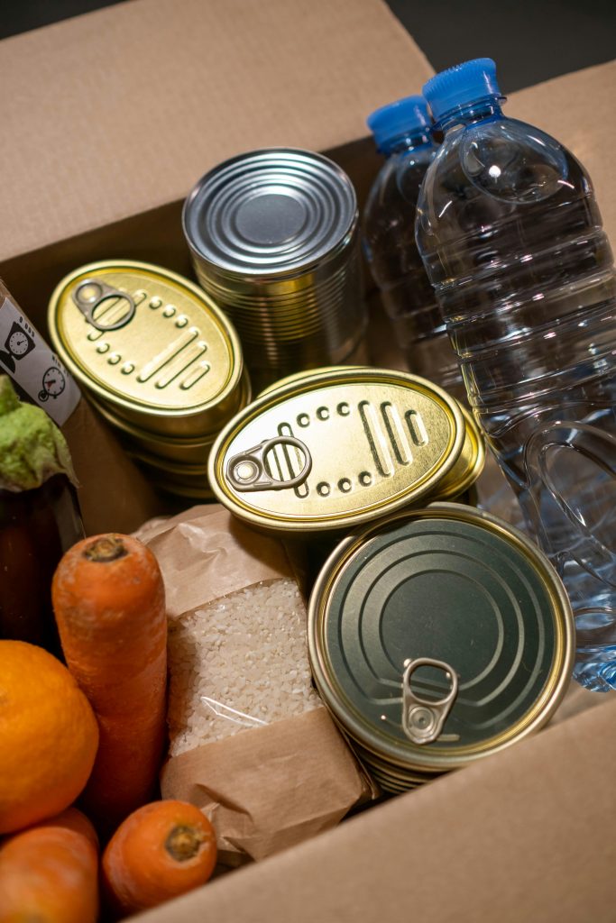 pexels-photo-6590914-6590914-2 Box filled with essential food items including canned goods and fresh produce.